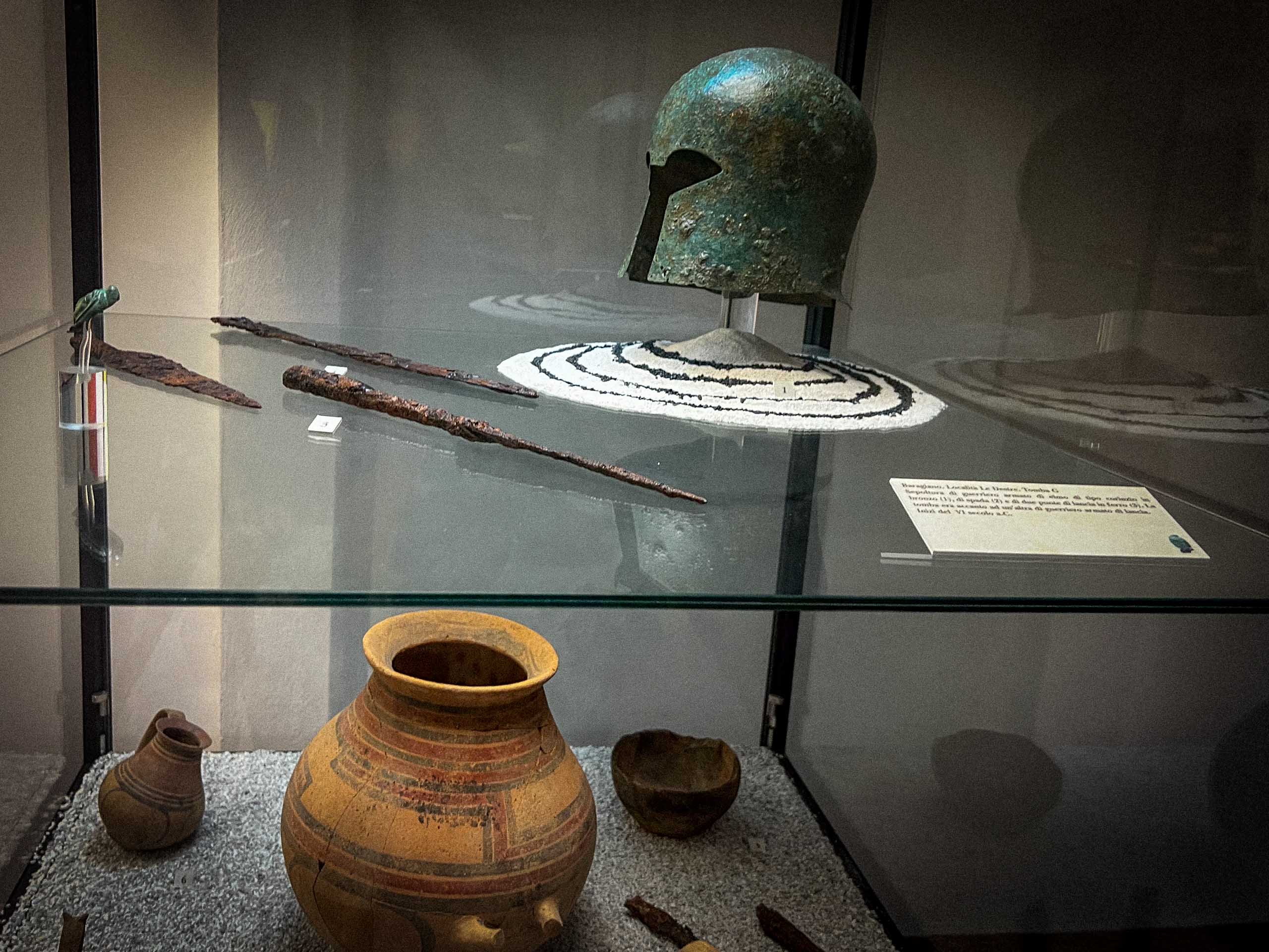 vetrina con elmo, spade e vasi, sepoltura di guerriero, esposto nel Museo archeologico nazionale di Muro Lucano