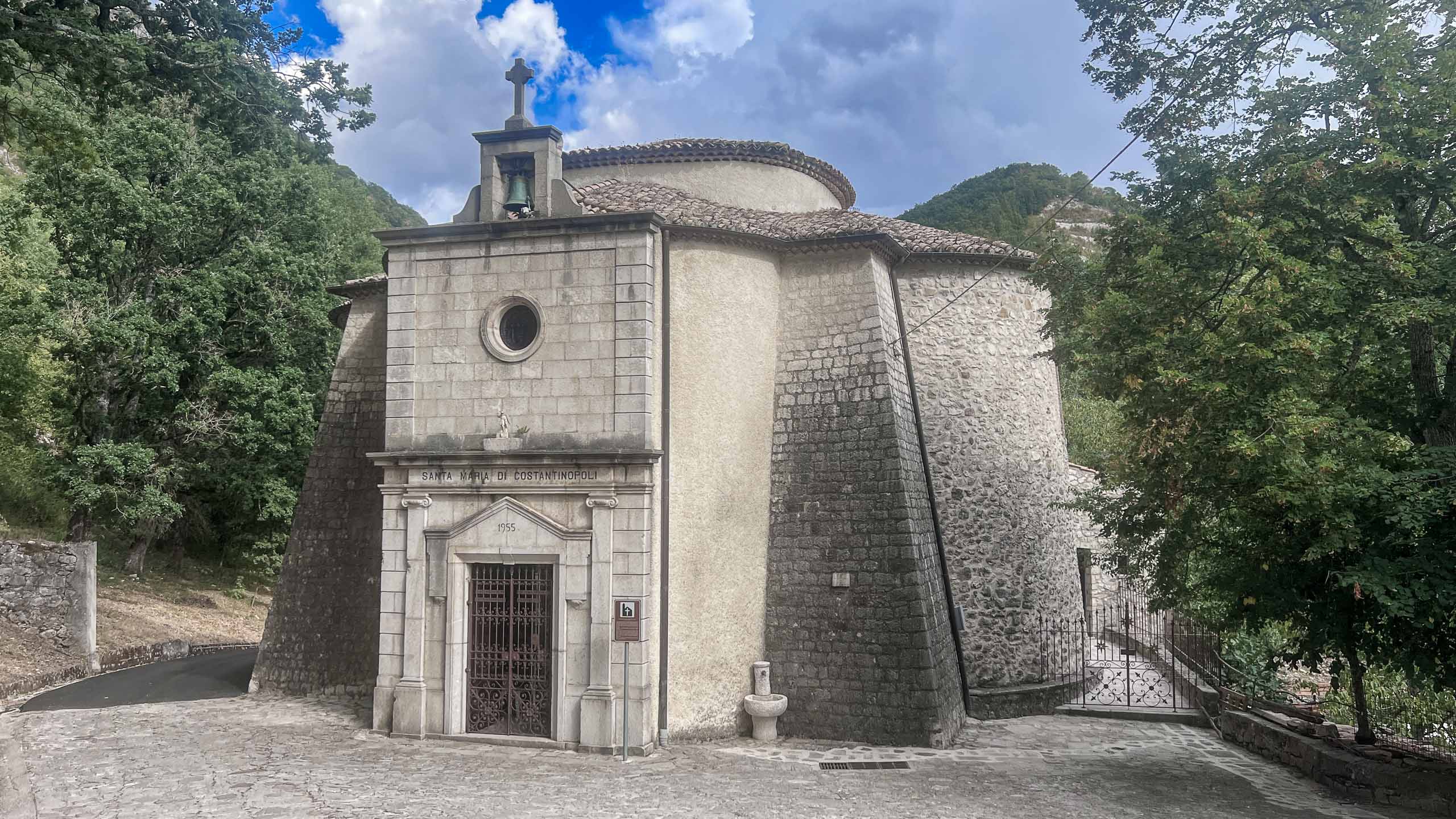 facciata in pietra con portale, oculo e campanile a vela, contrafforti laterali a scarpa, corpo absidale curvo sul retro